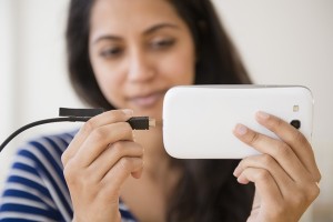 Close up of Asian woman connecting cell phone to battery