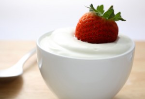 A fresh strawberry dipped in a bowl of yogurt.